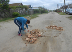В Камышине жители непроезжей, неасфальтированной улицы вышли перед праздниками забивать ямы кирпичами