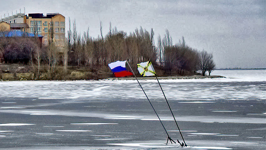 Символические флаги на льду реки у Бородинского моста в Камышине наклонились от ветра, но их снова укрепили  металлическими конструкциями